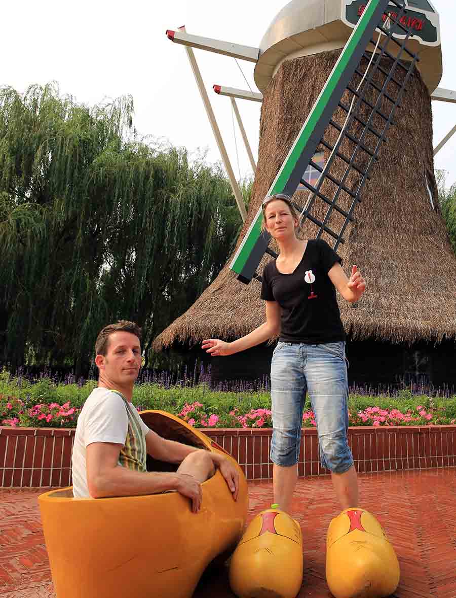 兩名外國游客在荷蘭風車前興致勃勃的試穿巨型鞋子