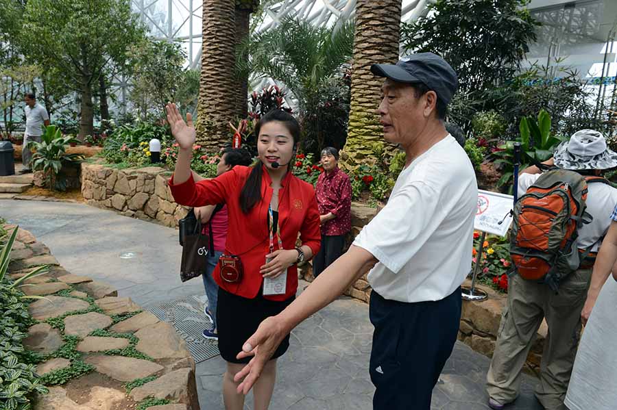 志愿者高燕在植物館里為游客講解館內(nèi)的各種珍稀植物
