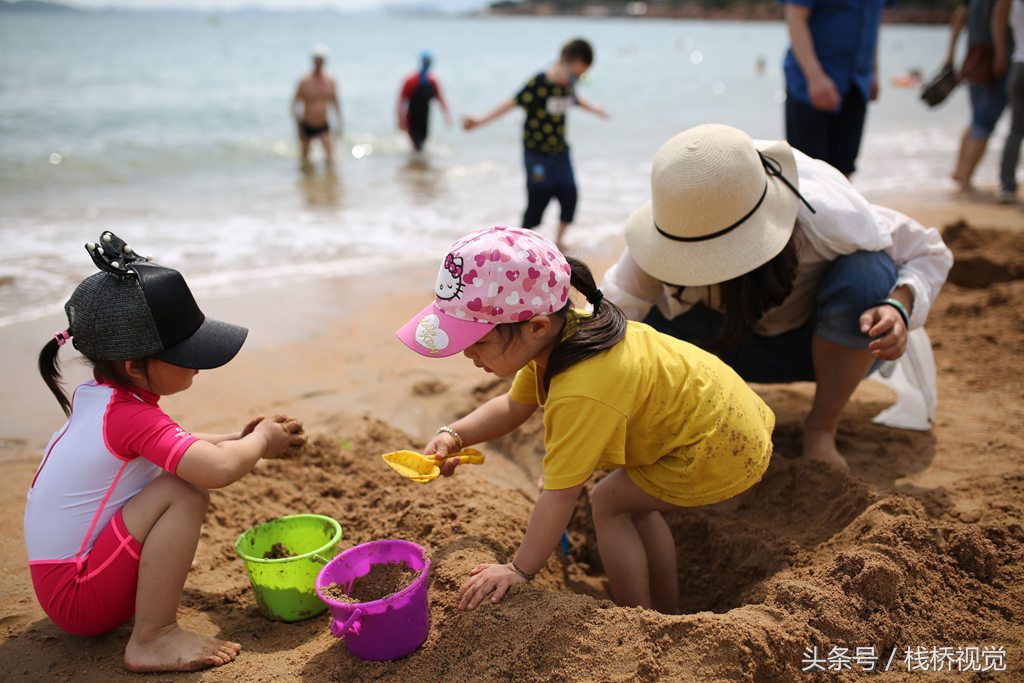 小朋友在青岛第一海水浴场戏水挖沙.