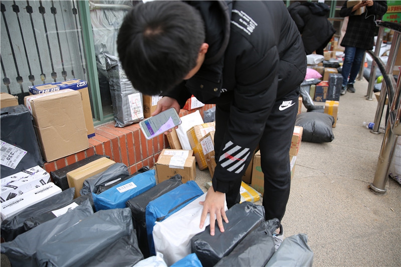 一大学生在根据手机收到的快递编号寻找自己的物品.